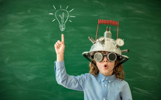 Back to school. Schoolchild with virtual reality headset in class. Funny kid against green blackboard. Innovation and creativity concept