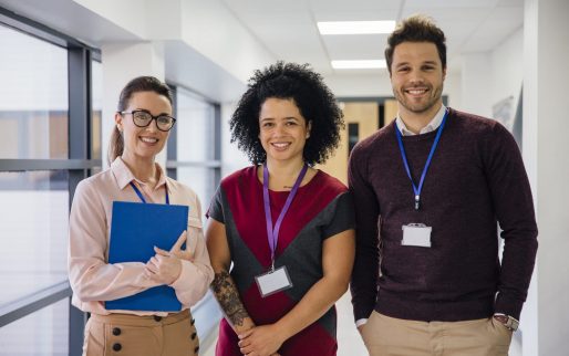 Portrait of three teachers in the school hall. They are smiling for the camera.