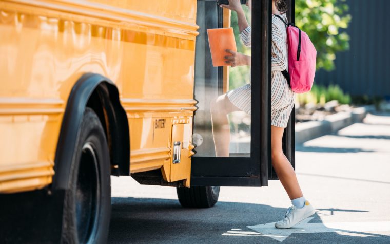 cropped shot of schoolgirl entering school bus