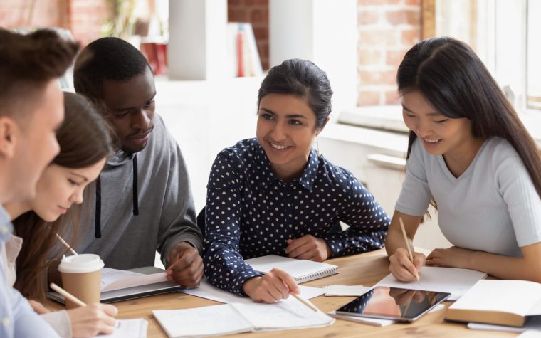 Focused multi national students studying together, team of girls and guys led by indian leader help with home work understanding, share ideas, offers creative approach to solve math challenge concept