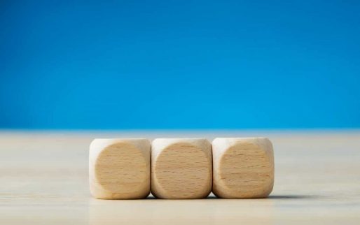 Wide view image of three blank wooden dices placed in a row. Over blue background with copy space.