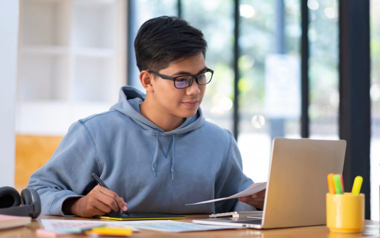 Young collage student using computer and mobile device studying online. Education and online learning.