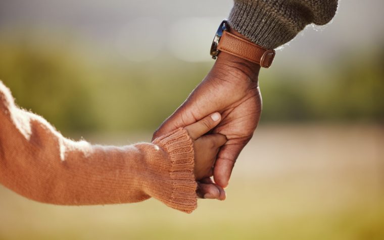 Family, holding hands and girl with father closeup in a park, hands and walking in nature, bond and relax outdoors. Love, trust and parent hands with child in support of trust, peace and unity.