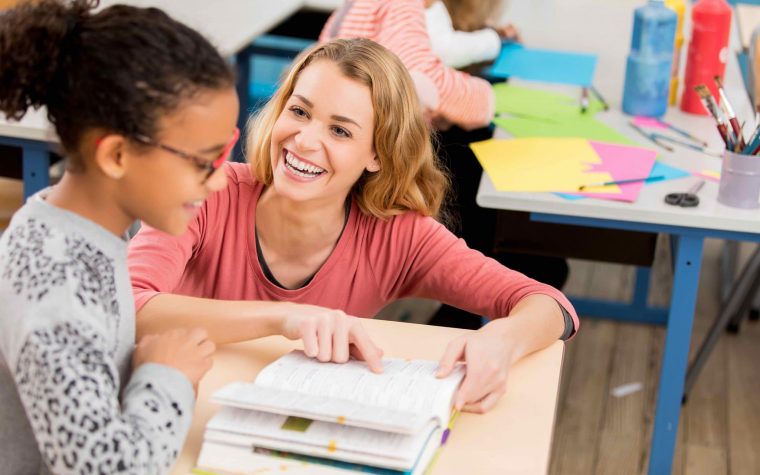 teacher helping schoolgirl at school