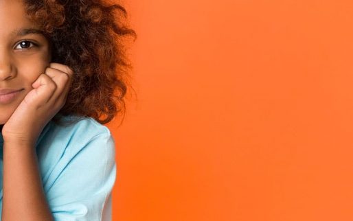 Half face portrait of schoolgirl with dark curly hair over orange background
