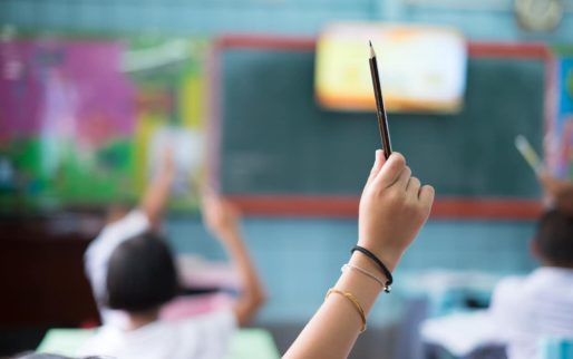 Student hands up asking a question in class at the elementary school. Education concept.