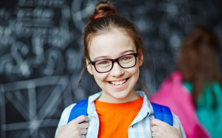 Happy little girl wearing glasses looking at camera