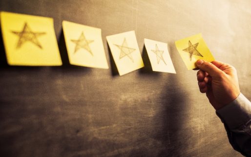 businessman attaching yellow  notes on blackboard with hand drawn stars