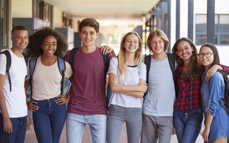 Teenage classmates standing in high school hallway